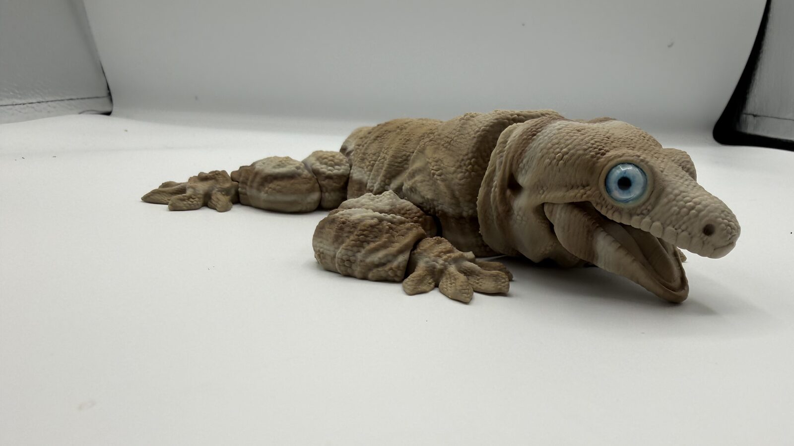 Tan articulated gecko with a large blue eye