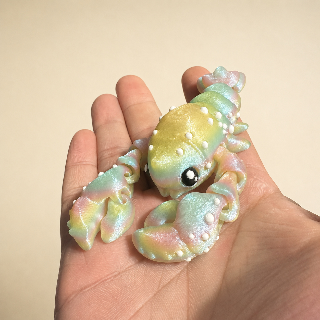 Pastel articulated creature held beside colorful filament spools